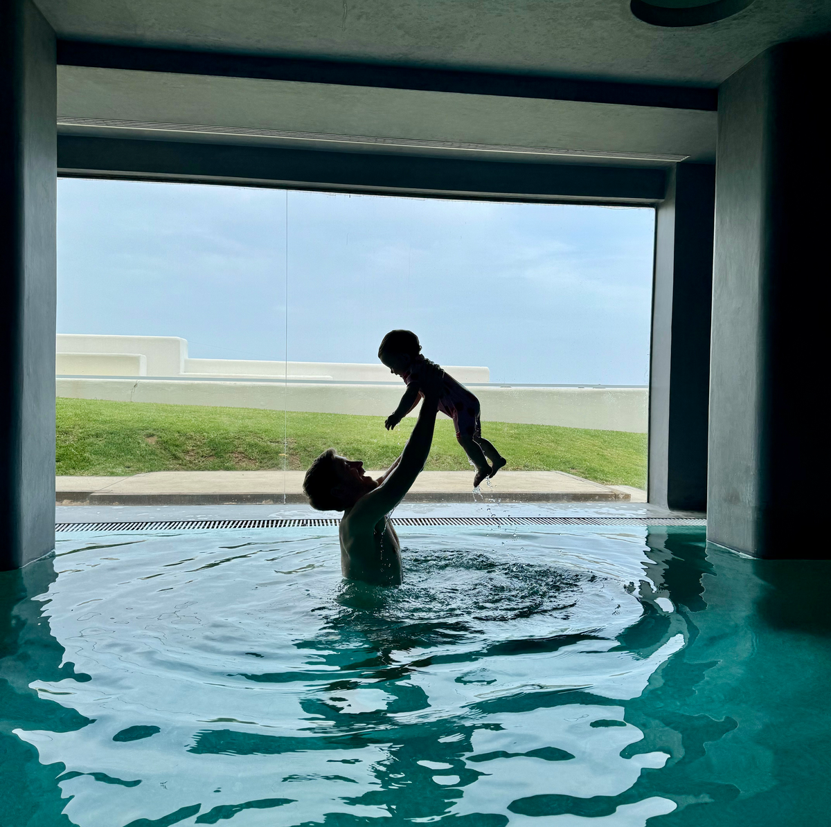 man holding up baby in swimming pool